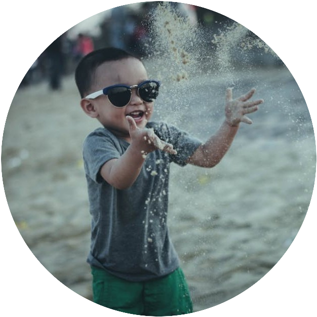 Child with sunglasses playing with sand